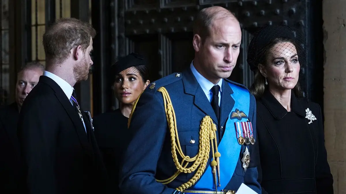 The Duke and Duchess of Sussex walking behind the Prince and Princess of Wales as they all look serious during Queen Elizabeth's funeral.