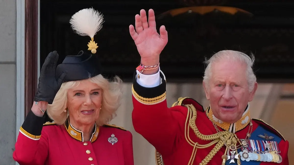 King Charles III and Queen Camilla waving from Buckingham Palace balcony