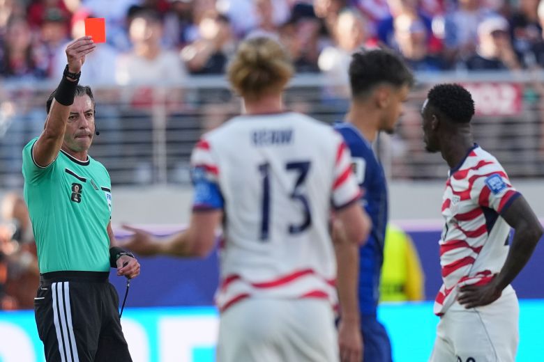 Referee Raphael Claus shows a red card to Balogun after a VAR review.