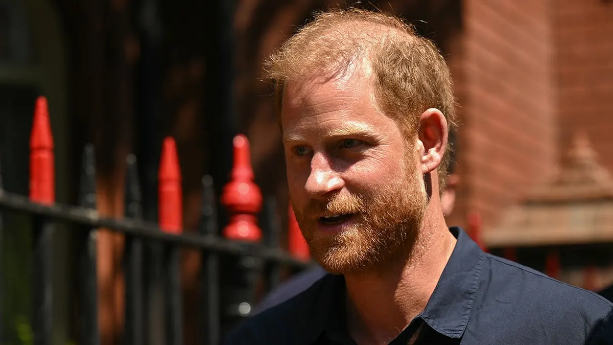 A close-up of Prince Harry outside in a dark blue shirt.