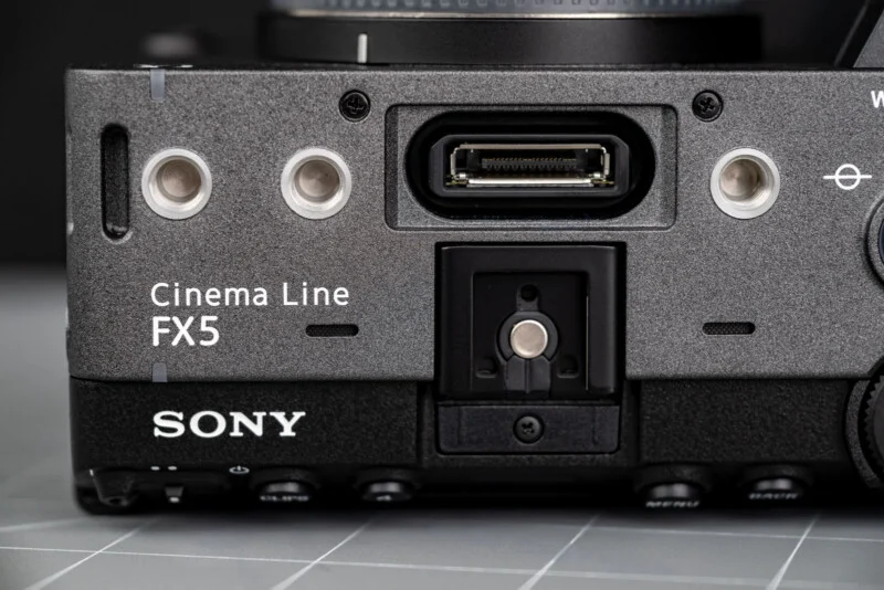 Close-up of a Sony Cinema Line FX5 camera body, showing connection ports and mounting points on a gray surface.