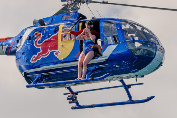 This image released by Discovery Channel shows high diver Molly Carlson preparing to leap 50 feet from a helicopter into a cage surrounded by reef sharks in an episode for Discovery's annual