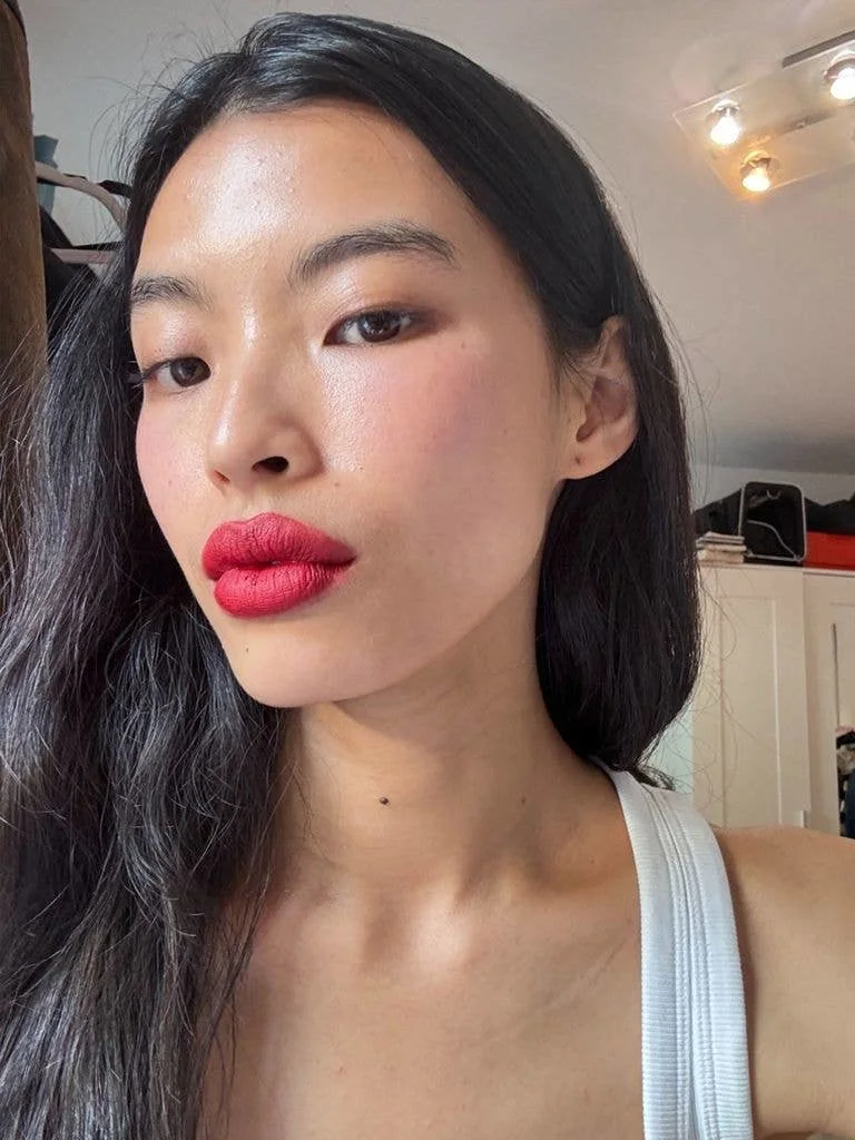 Beauty Thet Thinn wearing red lipstick and a white top posing for a selfie