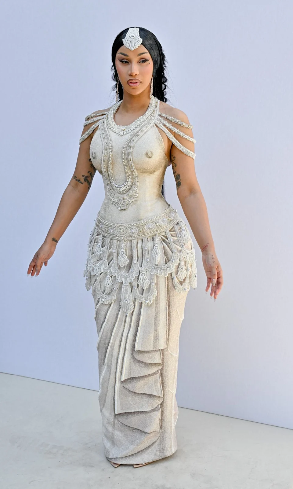 Cardi B turned heads in a cream embroidered dress paired with strappy heels, delivering an elegant yet eye-catching look that reflected her signature glamorous style.