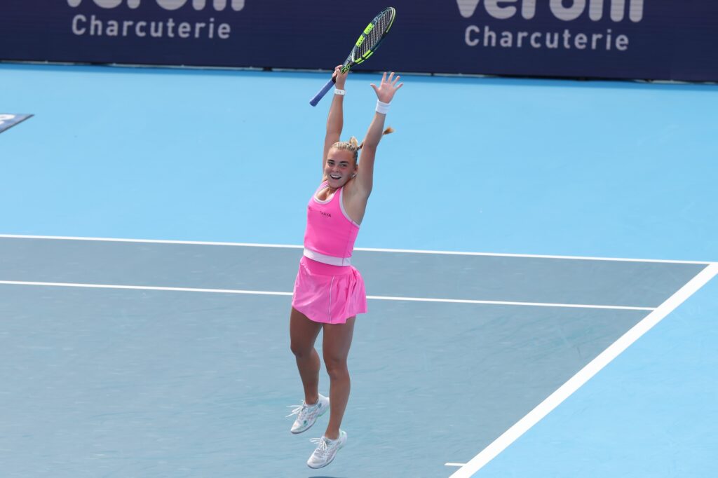 Sara Bejlek raises both arms while wearing pink