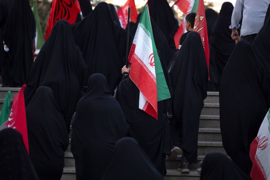 A veiled pro-government supporter carrying an Iranian national flag arrives to take part in a ceremony commemorating the memory of Iran's late Supreme Leader Ayatollah Ali Khamenei at the Imam Khomeini Grand Mosque in downtown Tehran, Iran, on August 18.