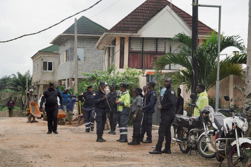 Security guards wait outside a building near Liberia's Roberts International Airport, as migrants arrive on a flight from the US on August 20.