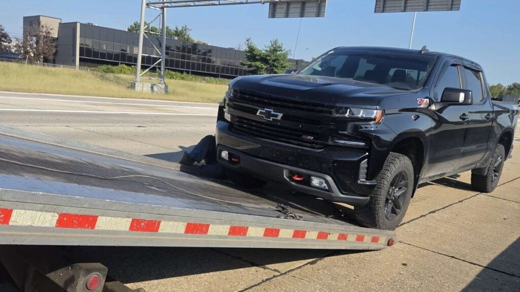 Steven's black Chevrolet Silverado Trail Boss shown beside a flatbed tow truck after its 6.2-liter V8 engine gave out at 98,876 miles, highlighting the high-mileage engine failure at the center of his ownership experience.