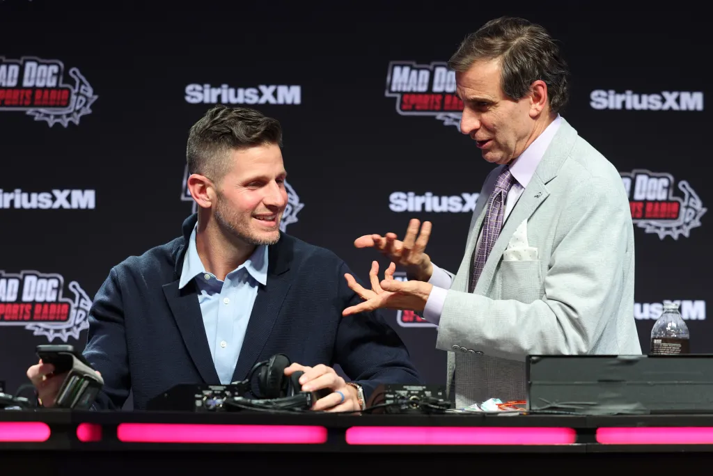 Chris Russo talking to a man at a SiriusXM broadcast table.