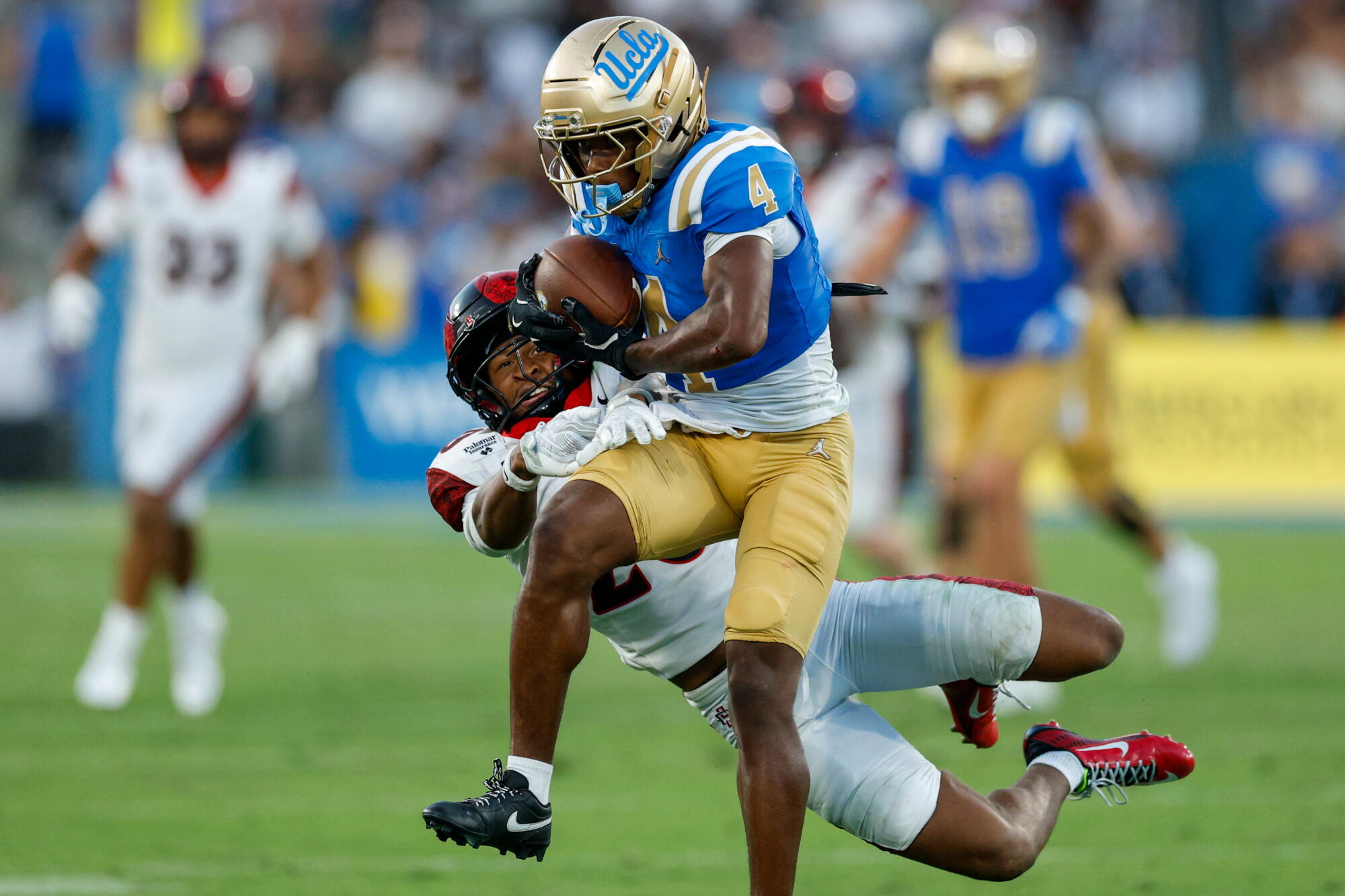 UCLA receiver Semaj Morgan makes a catch as San Diego State safety Jelani McLaughlin attempts to break it up.