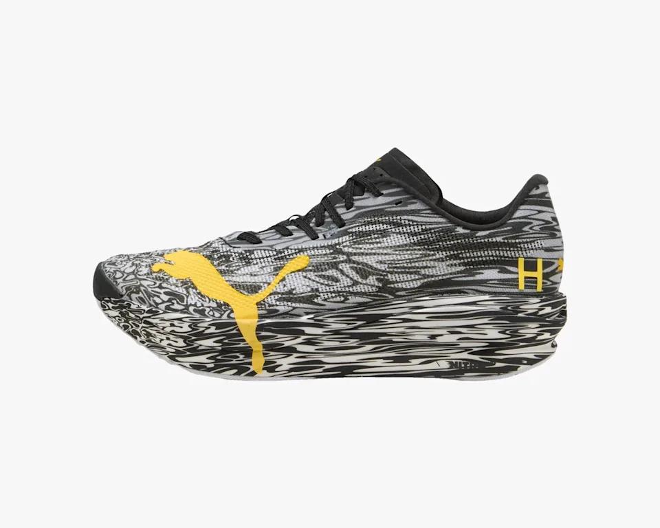 Puma running shoe featuring a black and white marbled pattern, a large yellow Puma logo on the side, and black laces.