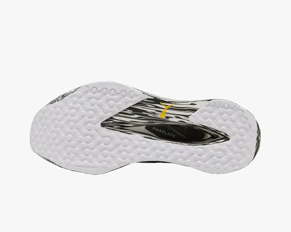 White and black patterned running shoe outsole featuring a textured grip, a yellow Puma logo, and a visible carbon fiber plate labeled PWRPLATE.