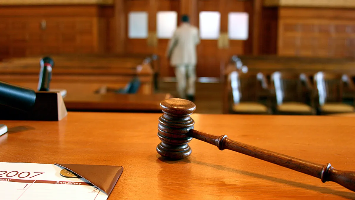 A gavel on a bench as people leave court