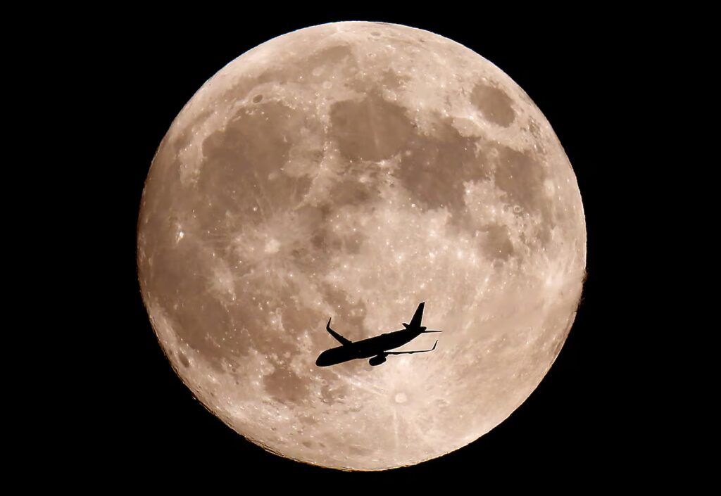 A nearly full Hunter's Moon rises over Halifax as a jet flies by on Oct. 16, 2024.