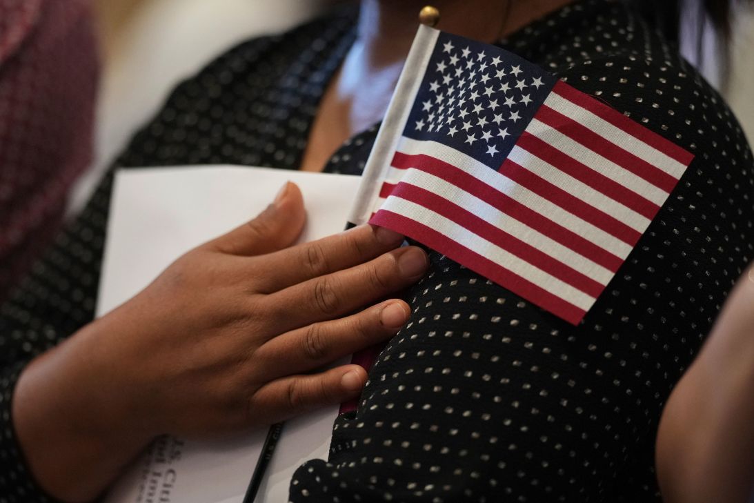 A woman clutches a US flag on July 3, 2025, as she and applicants from 20 countries prepare to take the oath of citizenship in San Antonio, Texas.
