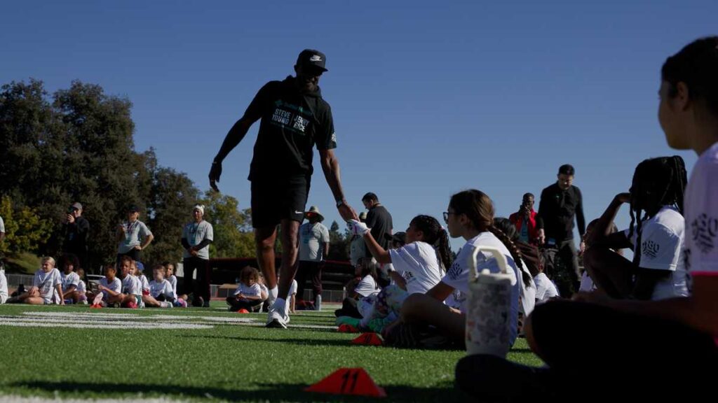 NFL Legends Steve Young and Jerry Rice hold flag football camp